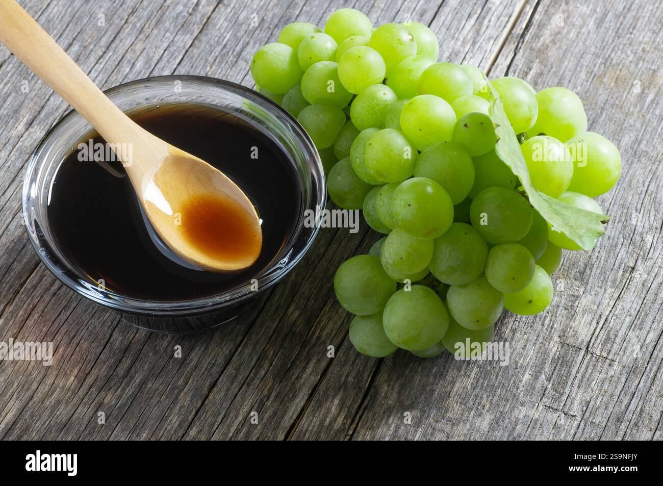 Bündel von frischen grünen Trauben und Traubenmelasse in Glas Schüssel auf rustikalem Hintergrund, Clipping Pfad. Konzept für Food Soße Stockfoto