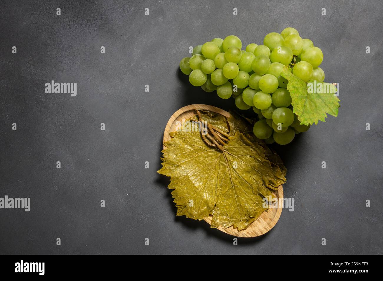 Traubenblatt in Schale mit frischen Traubenfrüchten auf rustikalem Hintergrund, türkisches eingelegtes Blatt wächst in Tokat, Soleblatt-Konzept Stockfoto