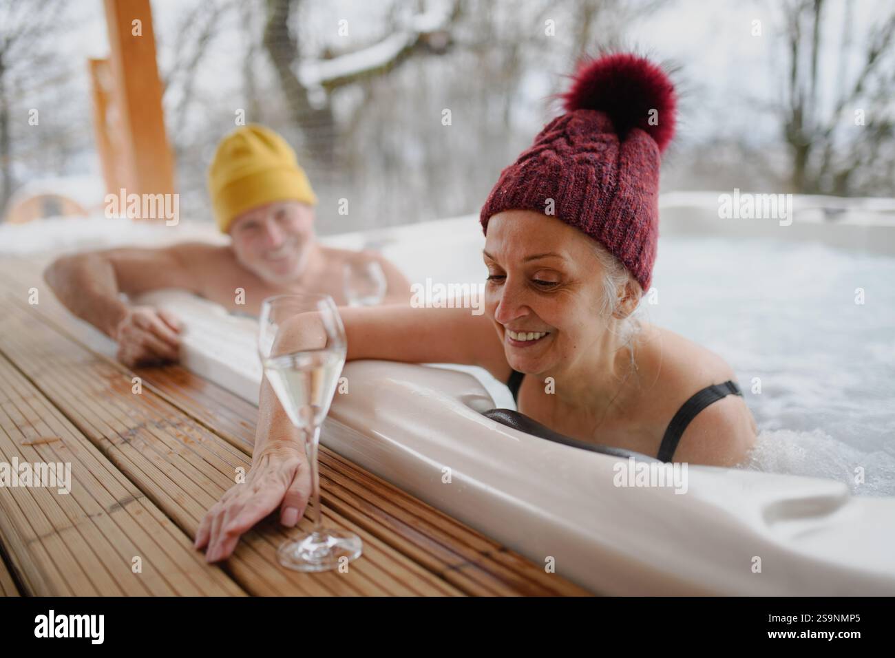 Reizende Senioren, die während des Badens im Whirlpool Champagner trinken. Romantischer Wellness-Kurzurlaub mit Spa am Valentinstag-Wochenende. Stockfoto