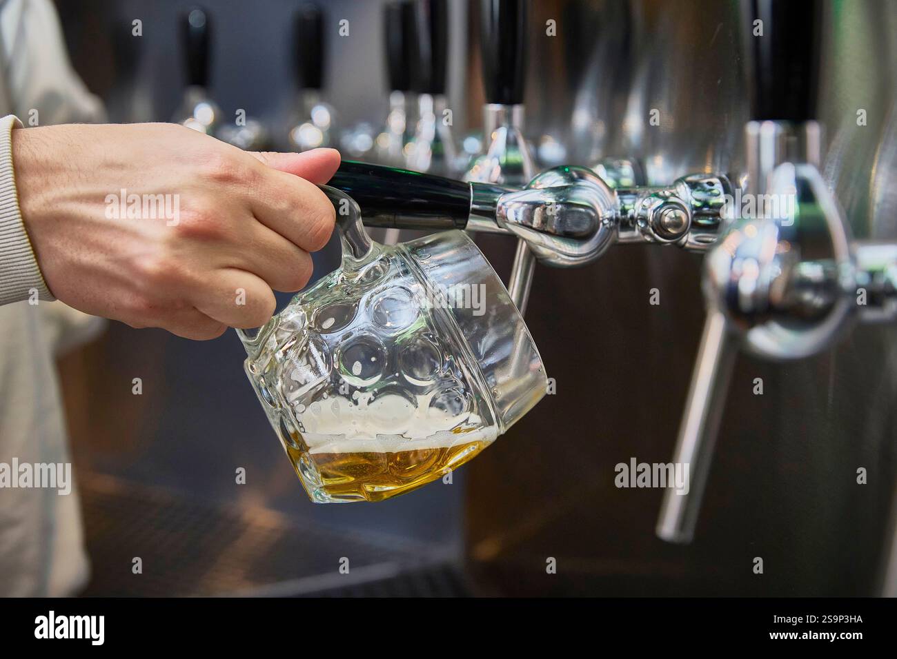 Eine Hand hält einen Becher Bier in einer Selbstbedienungs-Bierbar. Stockfoto