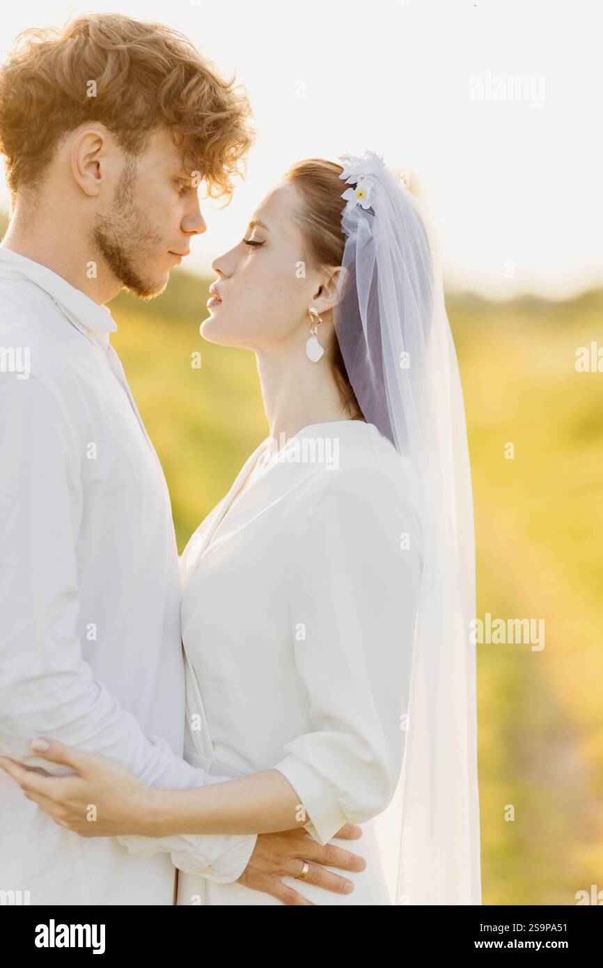 Ein kurzer Moment zwischen einem Paar draußen in Hochzeitskleidung mit goldenem Sonnenlicht Stockfoto