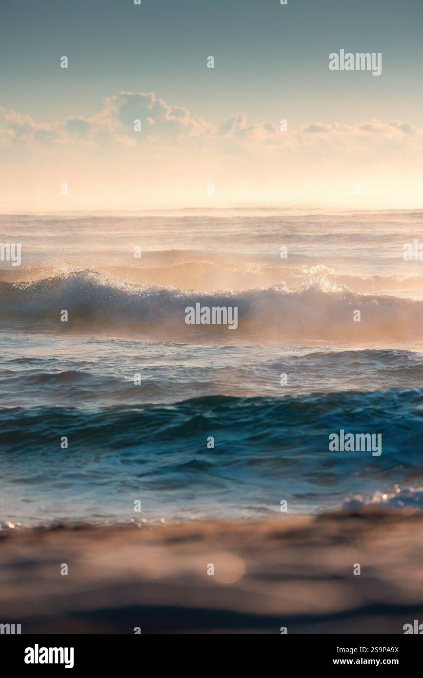 Wunderschöne Ozeanwellen, die während Eines Goldenen Sonnenuntergangs über ruhigen Gewässern gefangen wurden Stockfoto