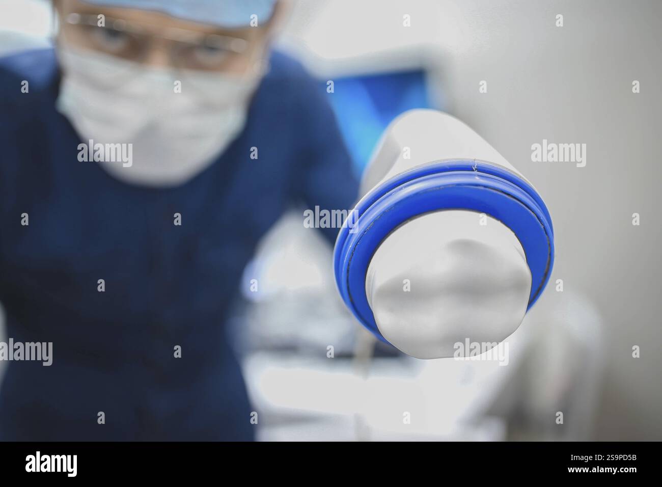 Chirurg, der ein medizinisches Werkzeug mit fokussiertem Ausdruck hält Stockfoto