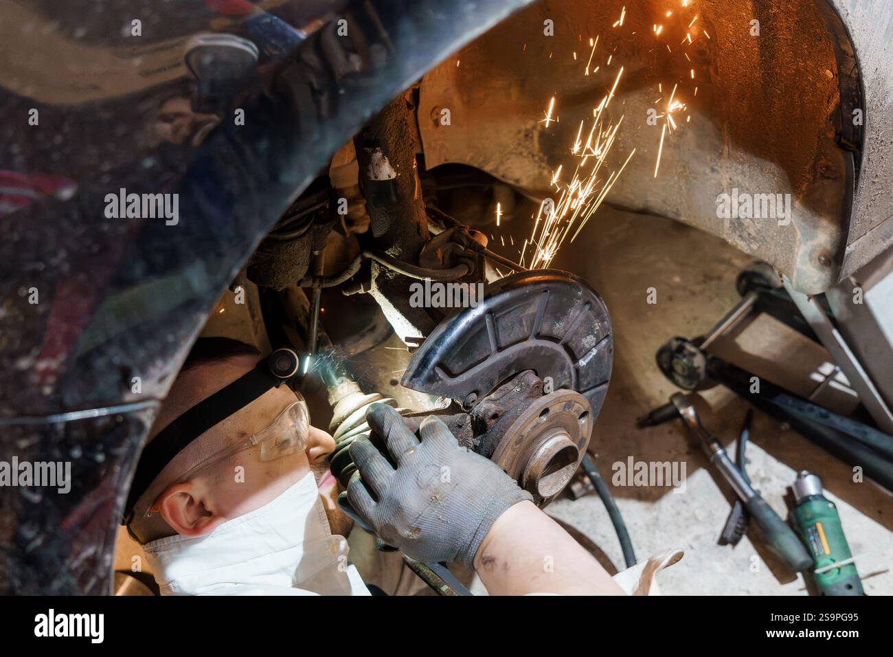 Ein Mechaniker, der die Wartung der Bremsen unter einem Fahrzeug durchführt. Stockfoto