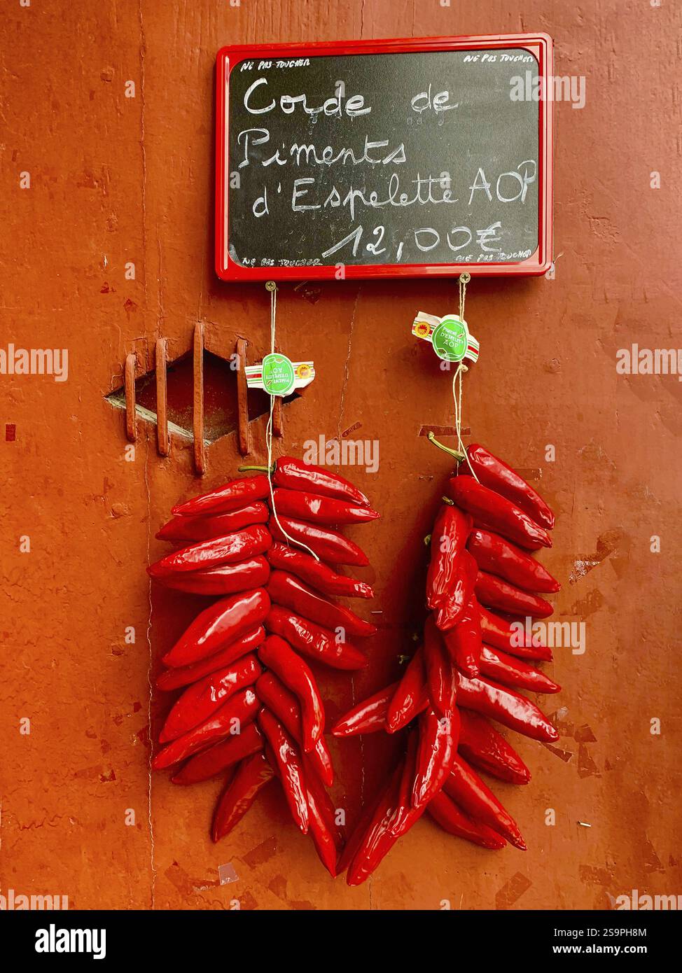 Cord of Piment dEspelette an einer Tür bei Espelette, Pays Baskisch, Pyrenäen-Atlantiques, Nouvelle-Aquitaine, Frankreich, Europa Stockfoto