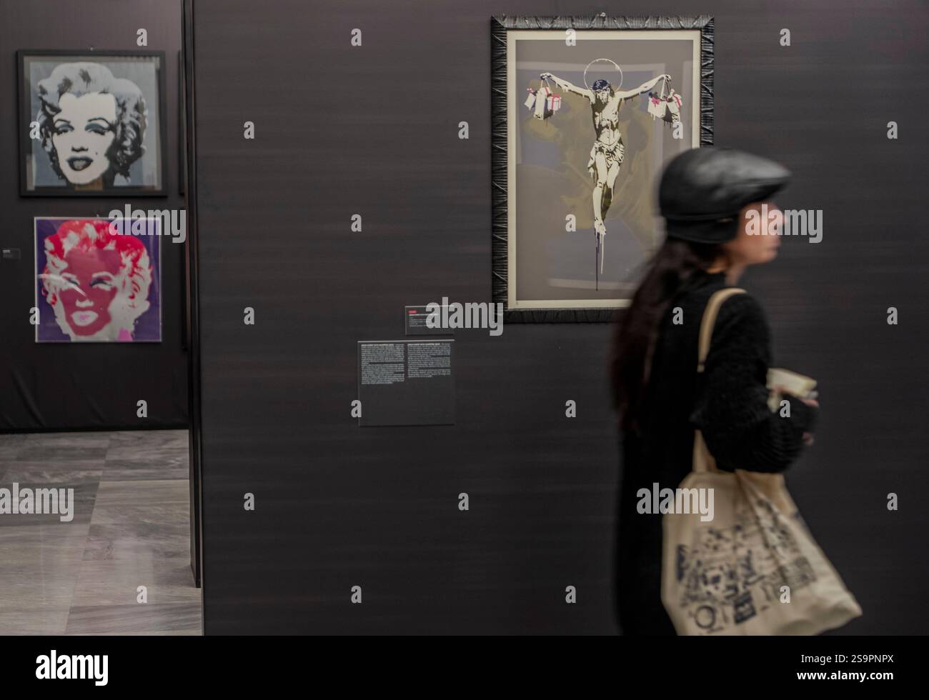 A visitor walks by Andy Warhol's This is not by Me, left, and Banksy's