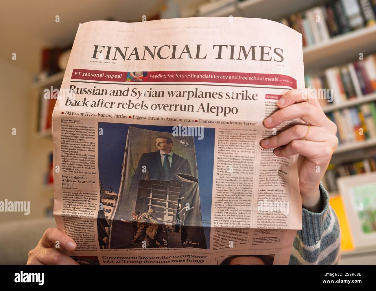 Paris, Frankreich - 9. Dezember 2024: Eine Person, die die Financial Times liest, mit einer Schlagzeile über russische und syrische Kampfflugzeuge, die zurückgeschlagen wurden, nachdem Rebellen überru Stockfoto