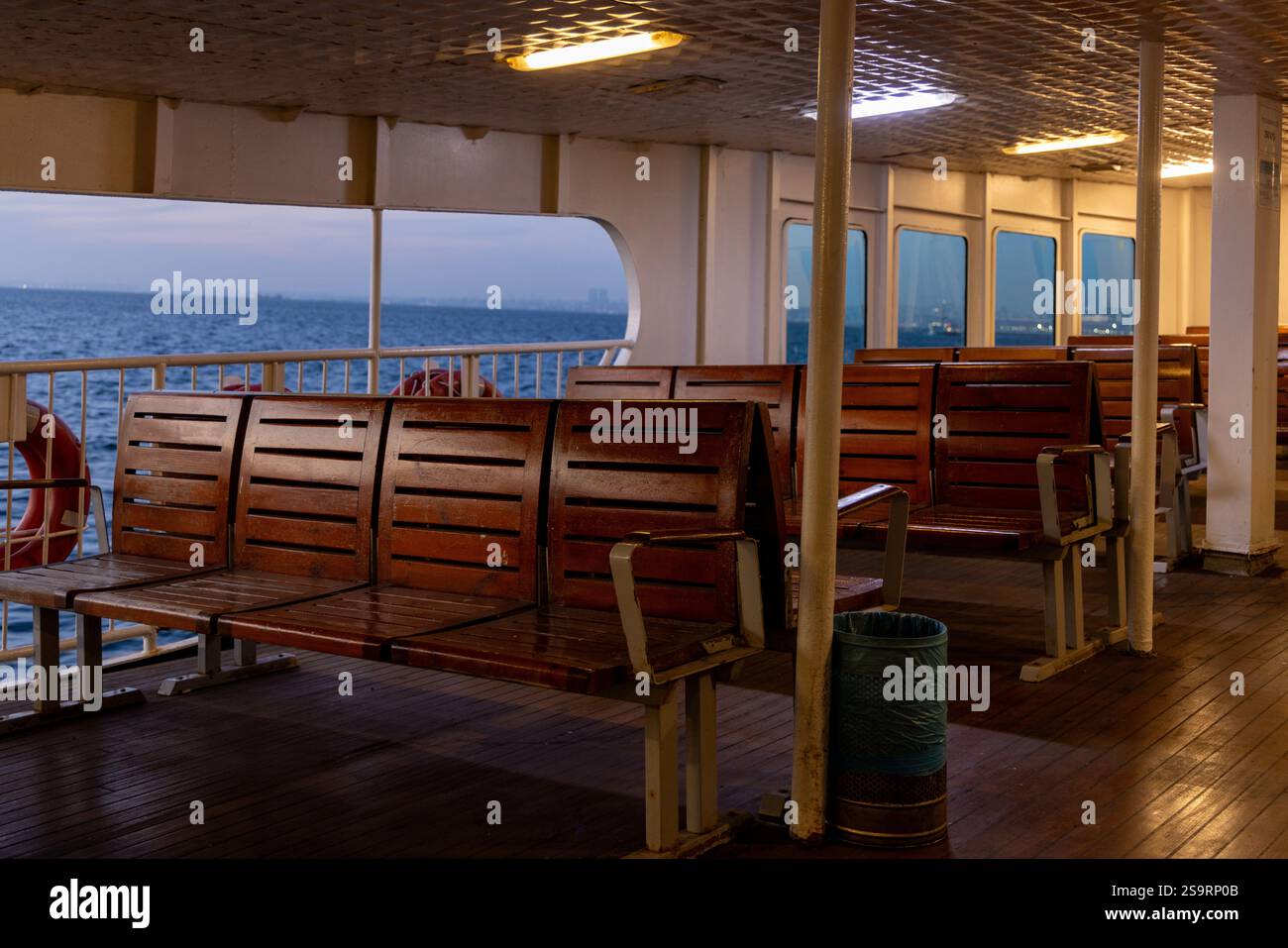 Ein leeres Fährdeck in Istanbul während der Dämmerung mit Blick auf das Marmarameer und entfernte Inseln. Ein ruhiger Moment, der das urbane maritime Leben veranschaulicht. Stockfoto