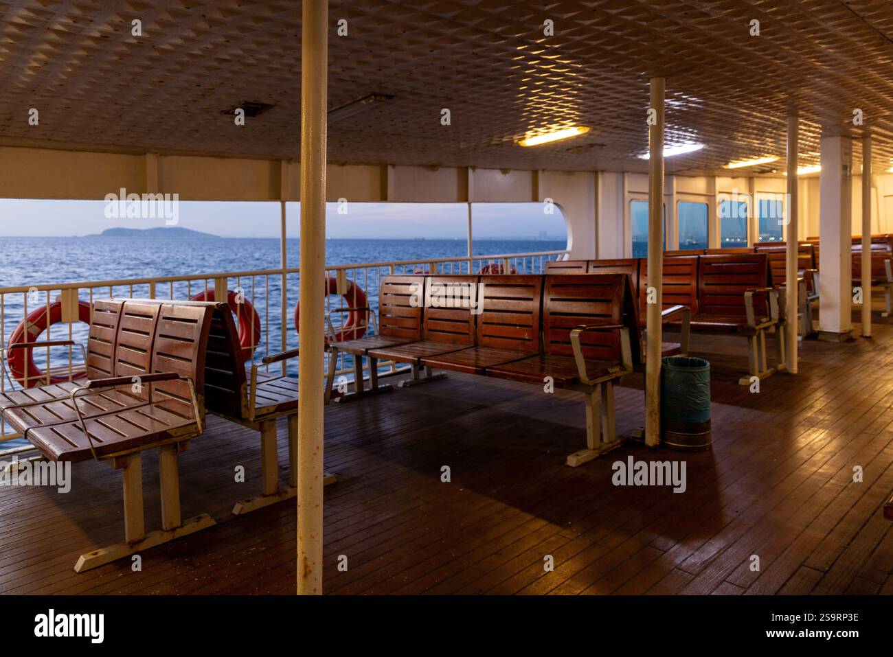 Ein leeres Fährdeck in Istanbul während der Dämmerung mit Blick auf das Marmarameer und entfernte Inseln. Ein ruhiger Moment, der das urbane maritime Leben veranschaulicht. Stockfoto