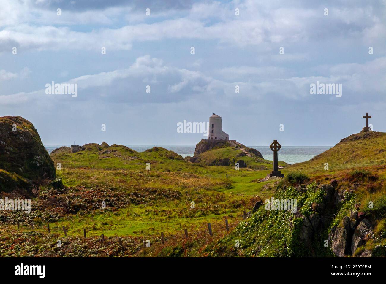 Hügelige Landschaft mit Kreuzen und Leuchtturm auf Ynys Llanddwyn, einer kleinen Insel vor der Küste von Anglesey in Nordwales, Großbritannien. Stockfoto