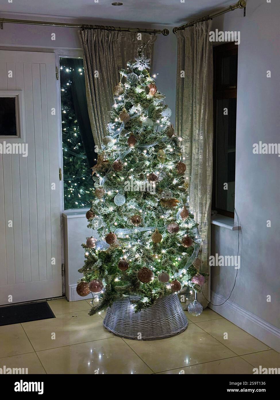 Weihnachtsbaum im modernen Stil mit kaltweißen Lichtern und Dekorationen aus schimmerndem und mattem Gold Stockfoto