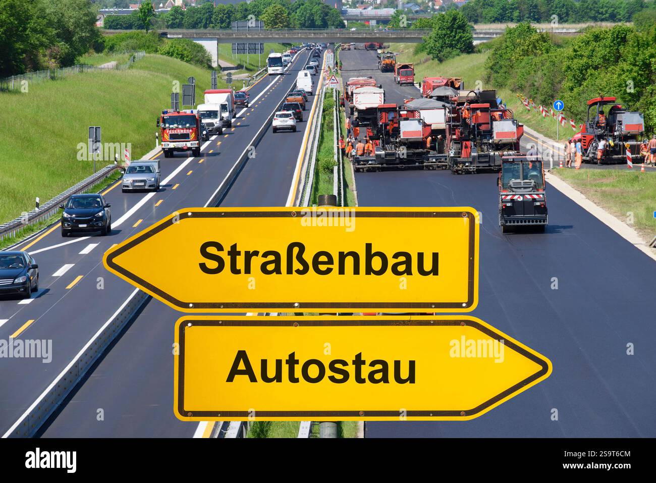 Straßenbau statt Autostau vor einer Autobahnbaustelle mit Autostau steht ein Richtungsweiser mit der Aufschrift Straßenbau und Autostau - FOTOMONTAGE Stockfoto