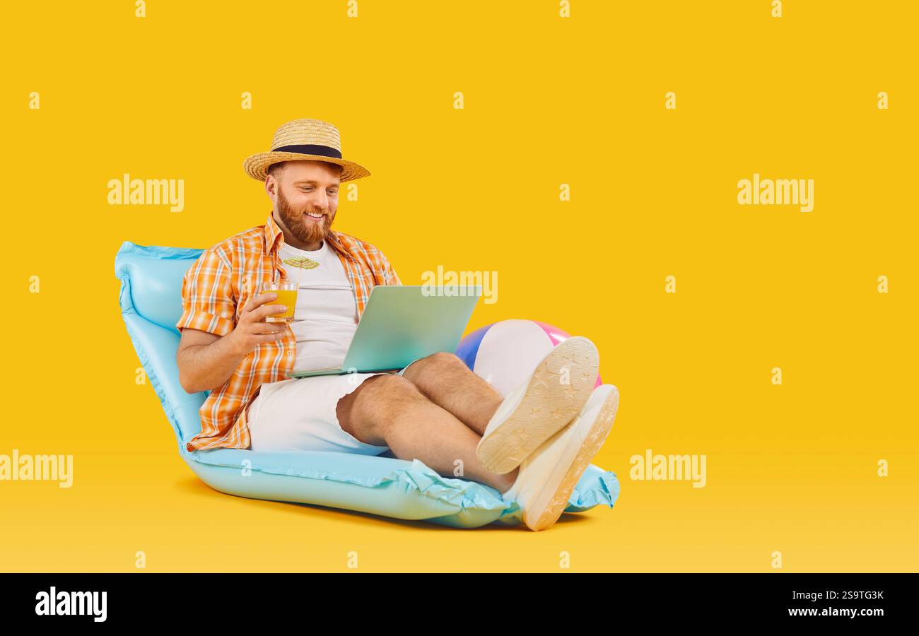 Positiver Mann, Der Sich Auf Aufblasbarer Matratze Mit Laptop Und Cocktail Entspannt Stockfoto