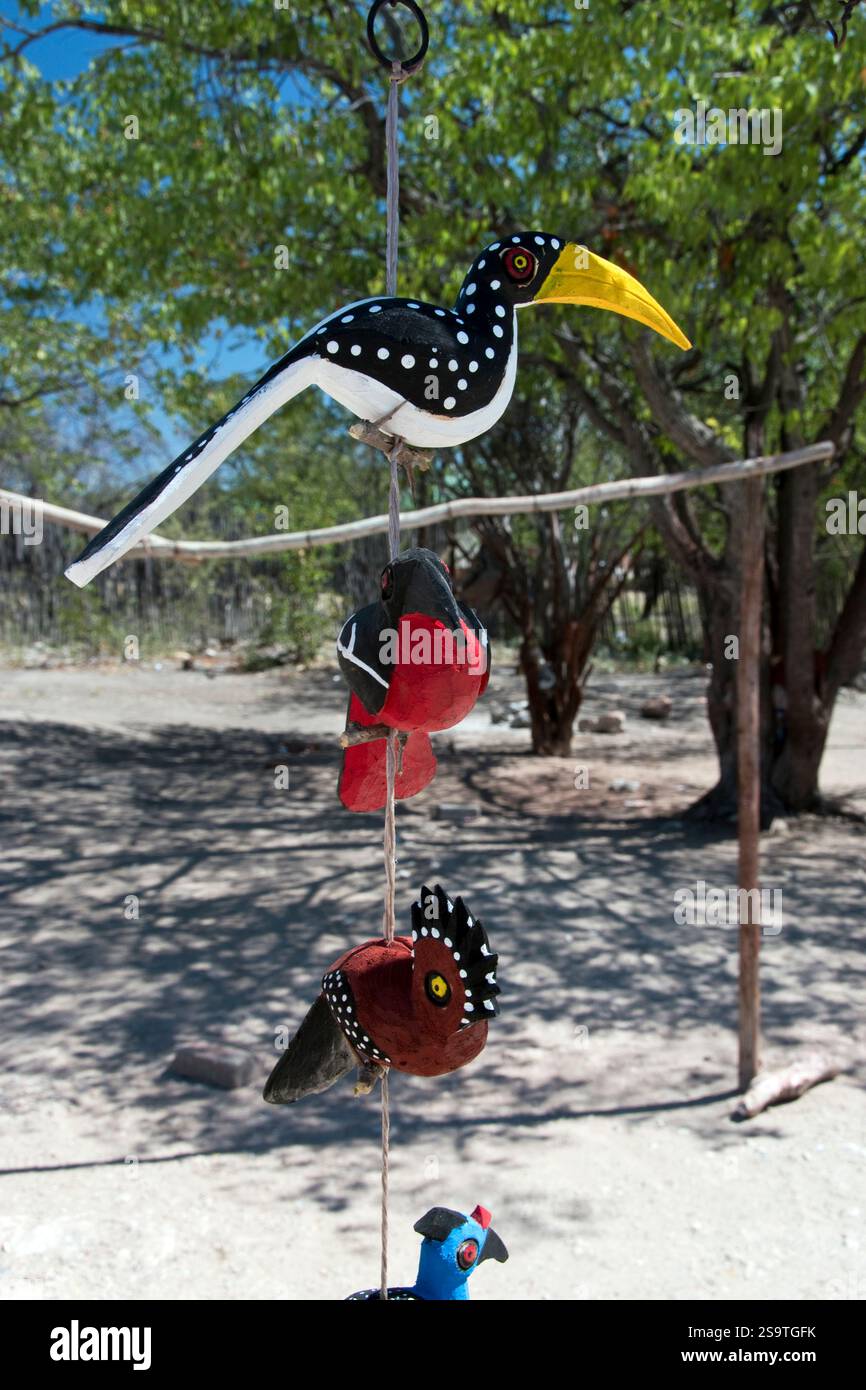 Geschnitzte und bemalte Holzvögel zum Verkauf vor dem Eingang des Andersson Gate zum Etosha Nationalpark im Norden Namibias. Stockfoto