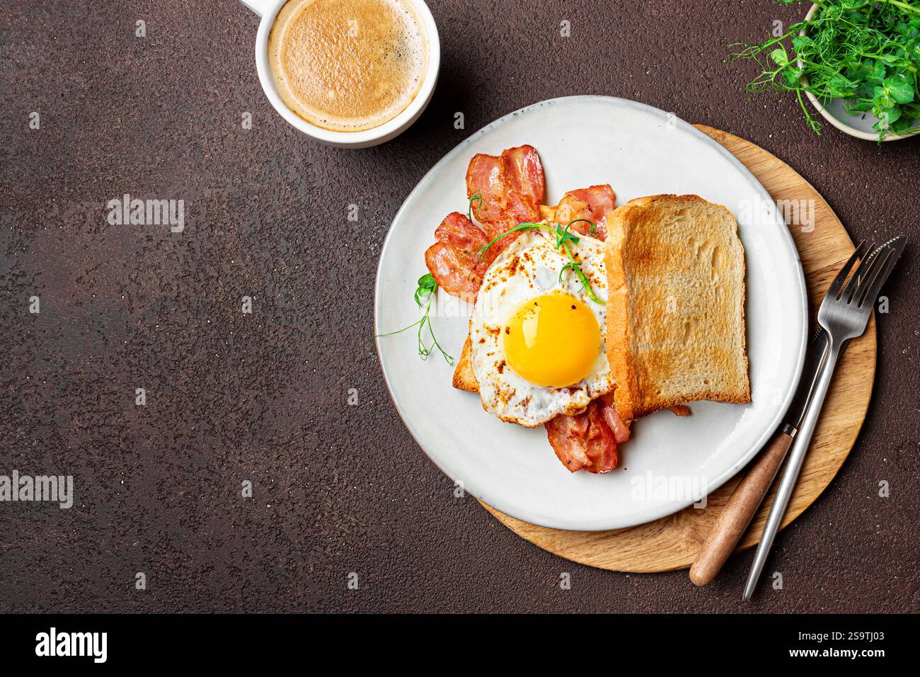 Gesundes Frühstück mit Spiegelei, Speck Sandmit und Mikrogrün auf dunklem Hintergrund, Kopierraum. Köstliches Spiegelei mit Speck auf Toast und Morgen c Stockfoto