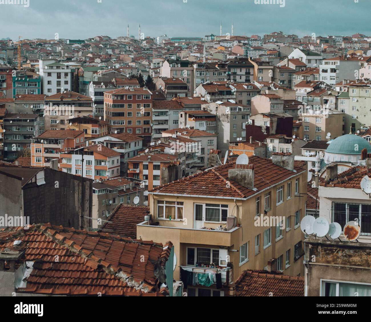 Atemberaubender Blick aus der Luft auf die Häuser in Istanbul bei Sonnenuntergang, während die warmen Farbtöne der untergehenden Sonne einen goldenen Glanz über die Dächer der Stadt ausstrahlen. Stockfoto