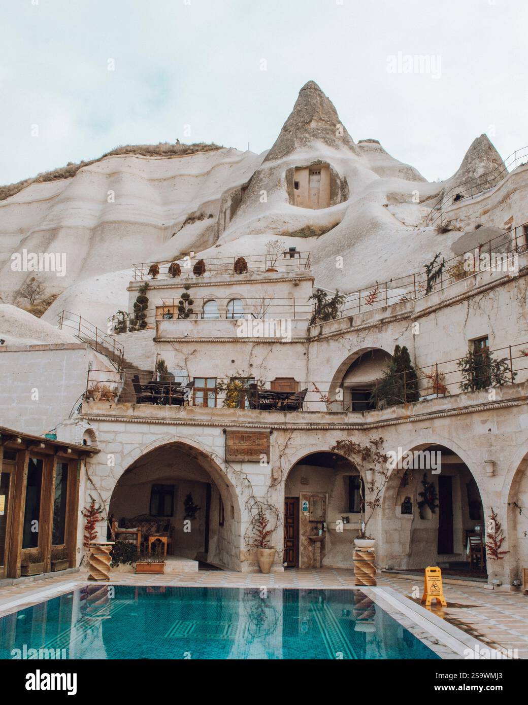Bezauberndes Foto eines lokalen Höhlenhaushotels mit erfrischendem Pool vor den einzigartigen Felsformationen von Kappadokien, Türkei. Stockfoto