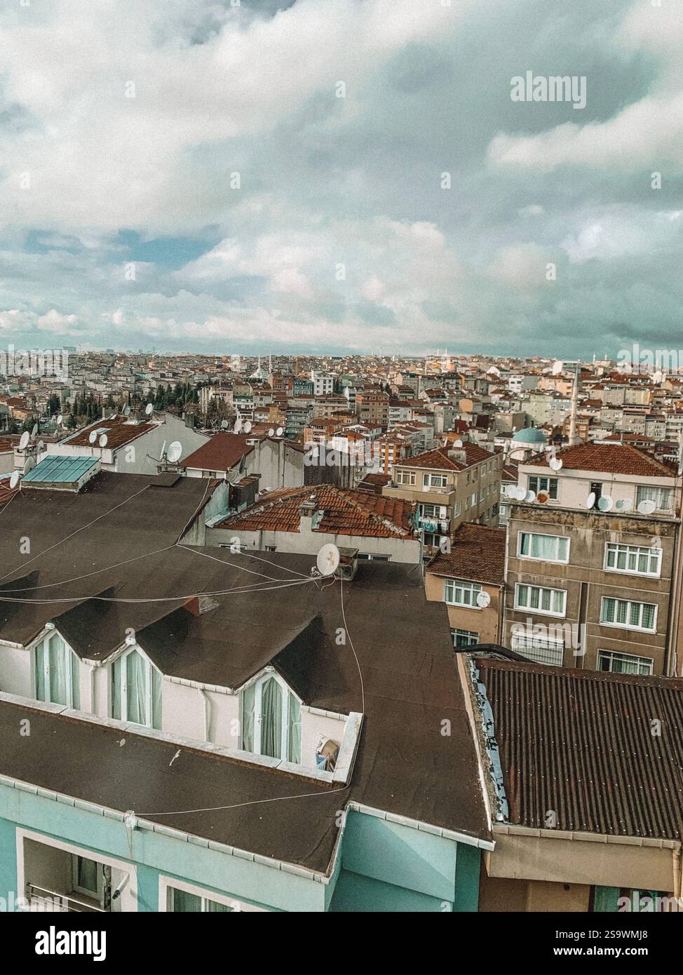 Atemberaubender Blick aus der Luft auf die Häuser in Istanbul bei Sonnenuntergang, während die warmen Farbtöne der untergehenden Sonne einen goldenen Glanz über die Dächer der Stadt ausstrahlen. Stockfoto