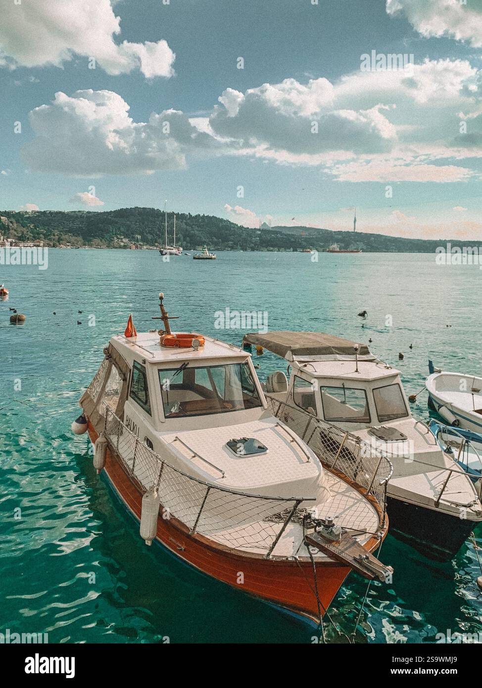 Ruhige Fotografie von Booten, die auf der Bosporusstraße in Istanbul schwimmen, mit der berühmten Skyline der Stadt im Hintergrund. Stockfoto