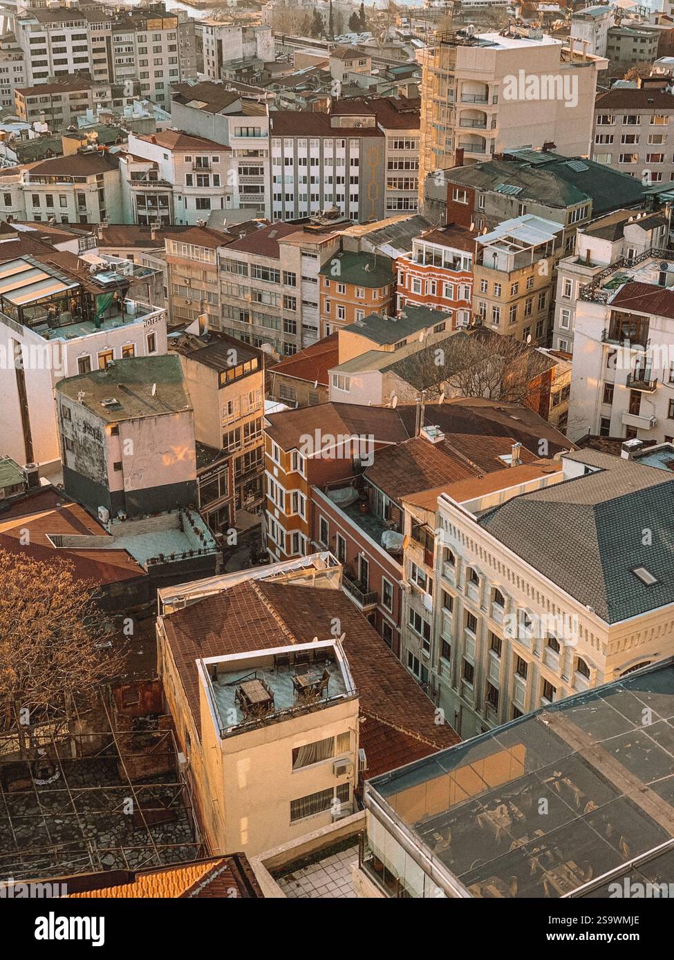 Atemberaubender Blick aus der Luft auf die Häuser in Istanbul bei Sonnenuntergang, während die warmen Farbtöne der untergehenden Sonne einen goldenen Glanz über die Dächer der Stadt ausstrahlen. Stockfoto
