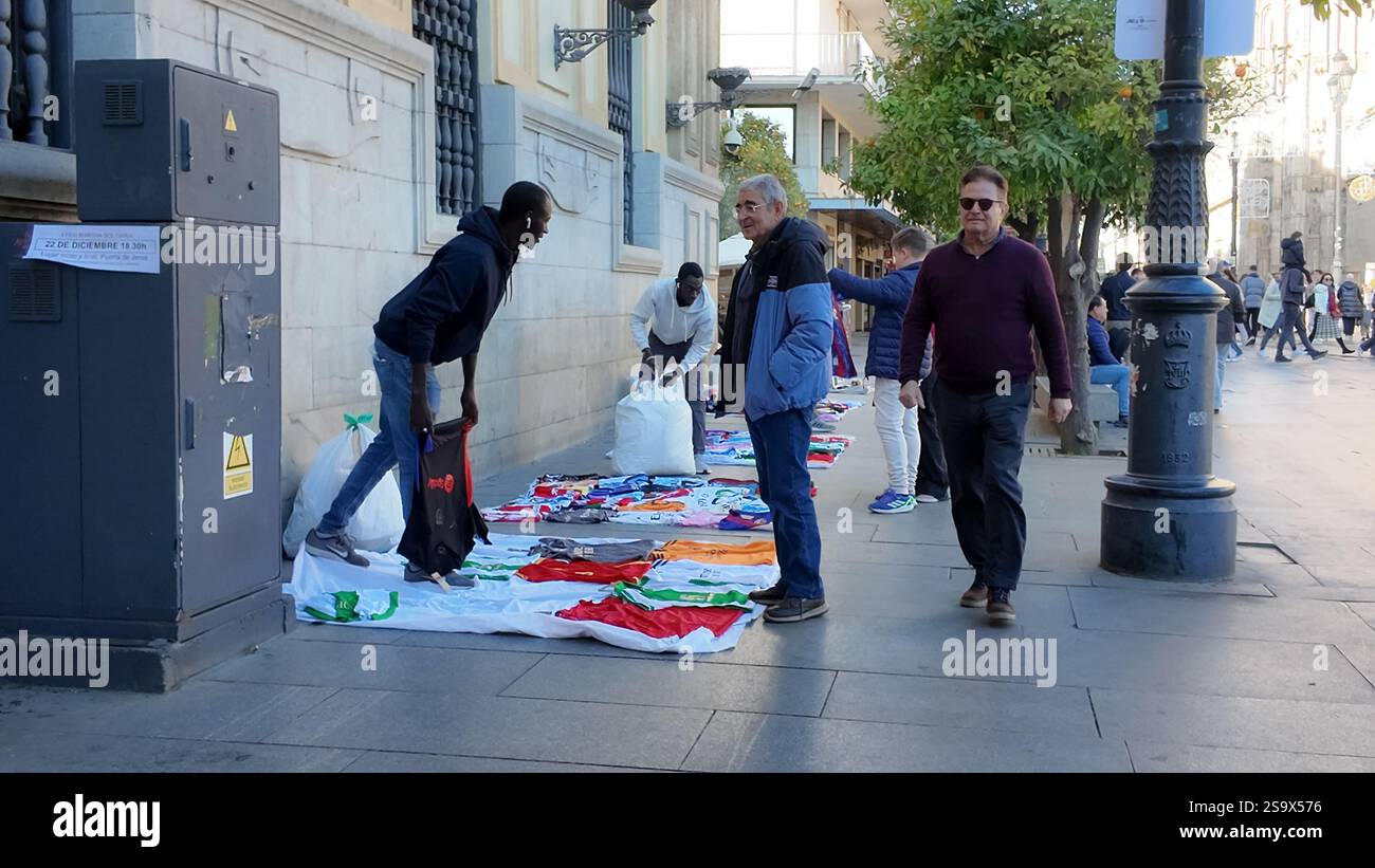 Ein illegaler Straßenverkäufer verkauft gefälschte Fußballtrikots auf einer Straße in Sevilla, Spanien. Stockfoto