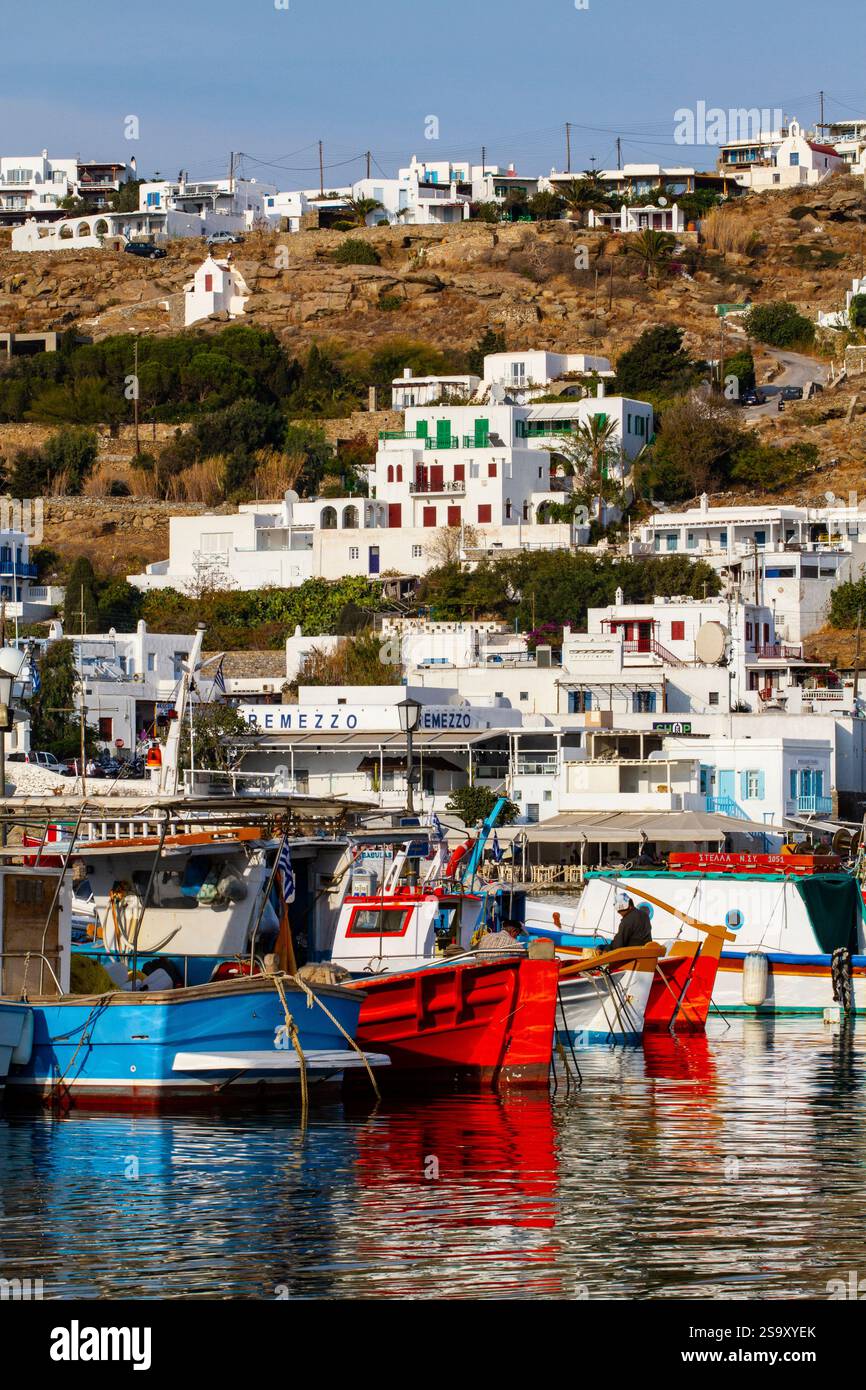 Mykonos, Griechenland. Blaue, rote und gestreifte Holzboote Fischerboote und Dorf an der Bucht Stockfoto