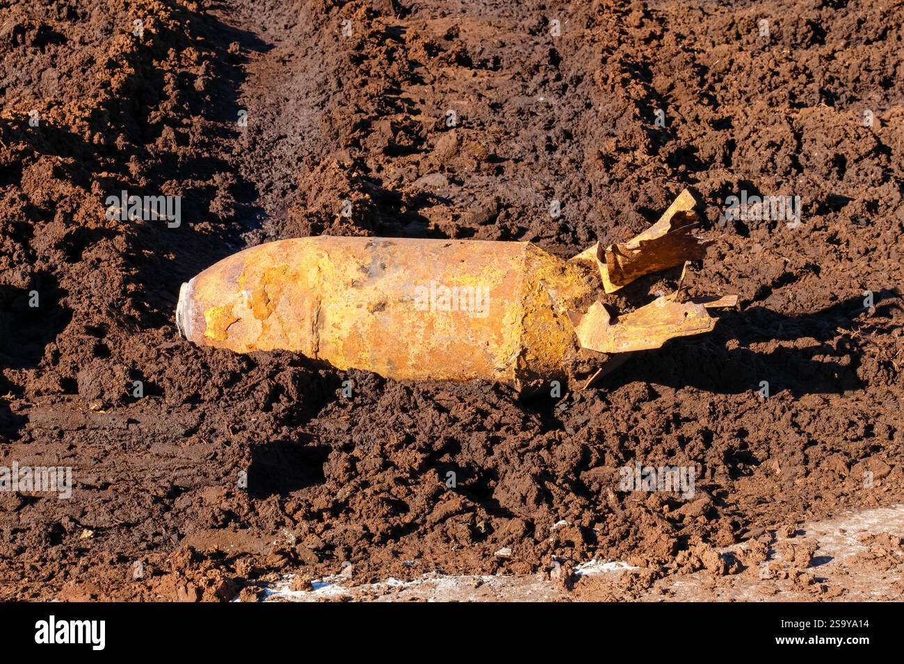 Verrostete Reliquienbombe aus dem Weltkrieg in matschigem Boden entdeckt, intensive Atmosphäre, Nahwinkel, historisches Artefakt aus Kriegszeiten auf kargem Feld, horizontal Stockfoto