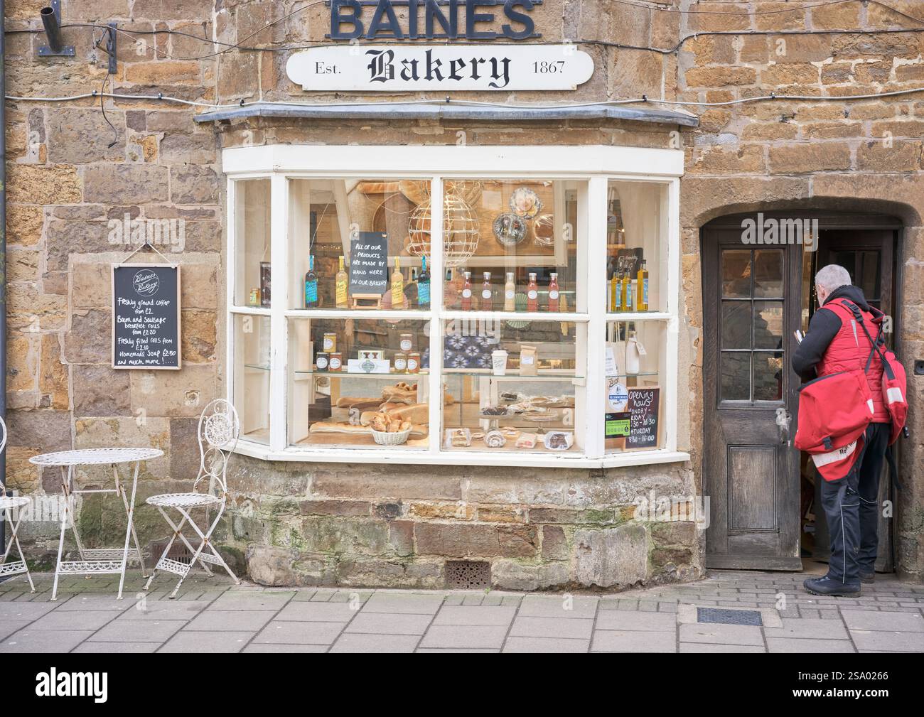 Postbote vor Baines Bakery Shop (gegründet 1867) in der Marktstadt Uppingham, England. Stockfoto