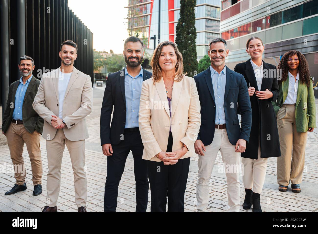 Verschiedene Gruppe von professionellen Einzelpersonen, die sich in stilvoller Kleidung für ein Unternehmensprofil in einem Bürogebäude mit Ausblick auf ihre Zukunft und gemeinsamen Bemühungen um Erfolg ausgeben. Hochwertige Fotos Stockfoto
