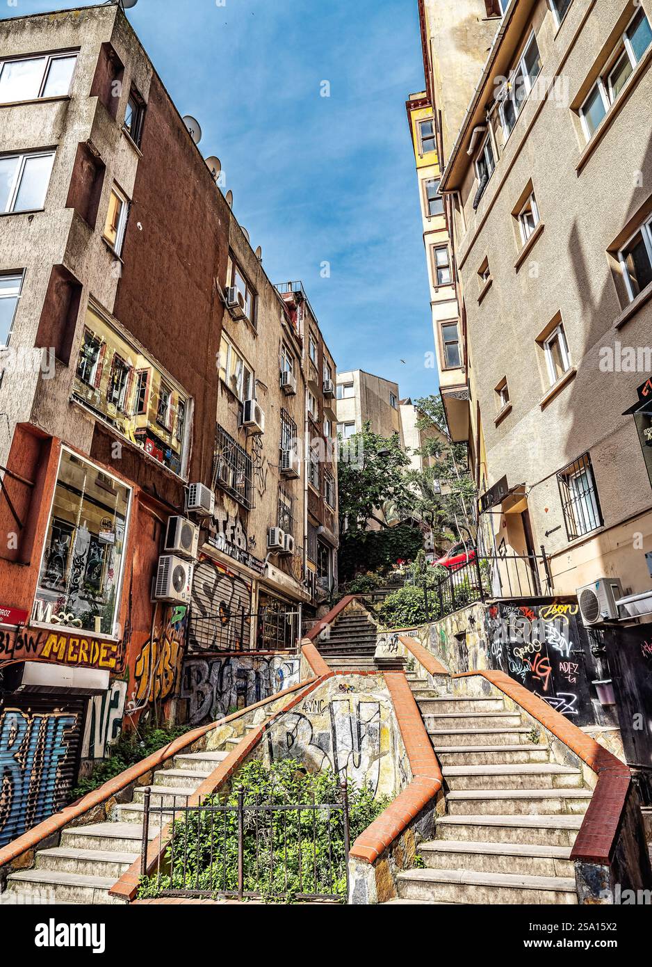 Eine steile Treppe im Freien zwischen städtischen Gebäuden mit lebendiger Straßenkunst unter hellem Tageslicht, die eine künstlerische und lebendige Atmosphäre darstellt Stockfoto
