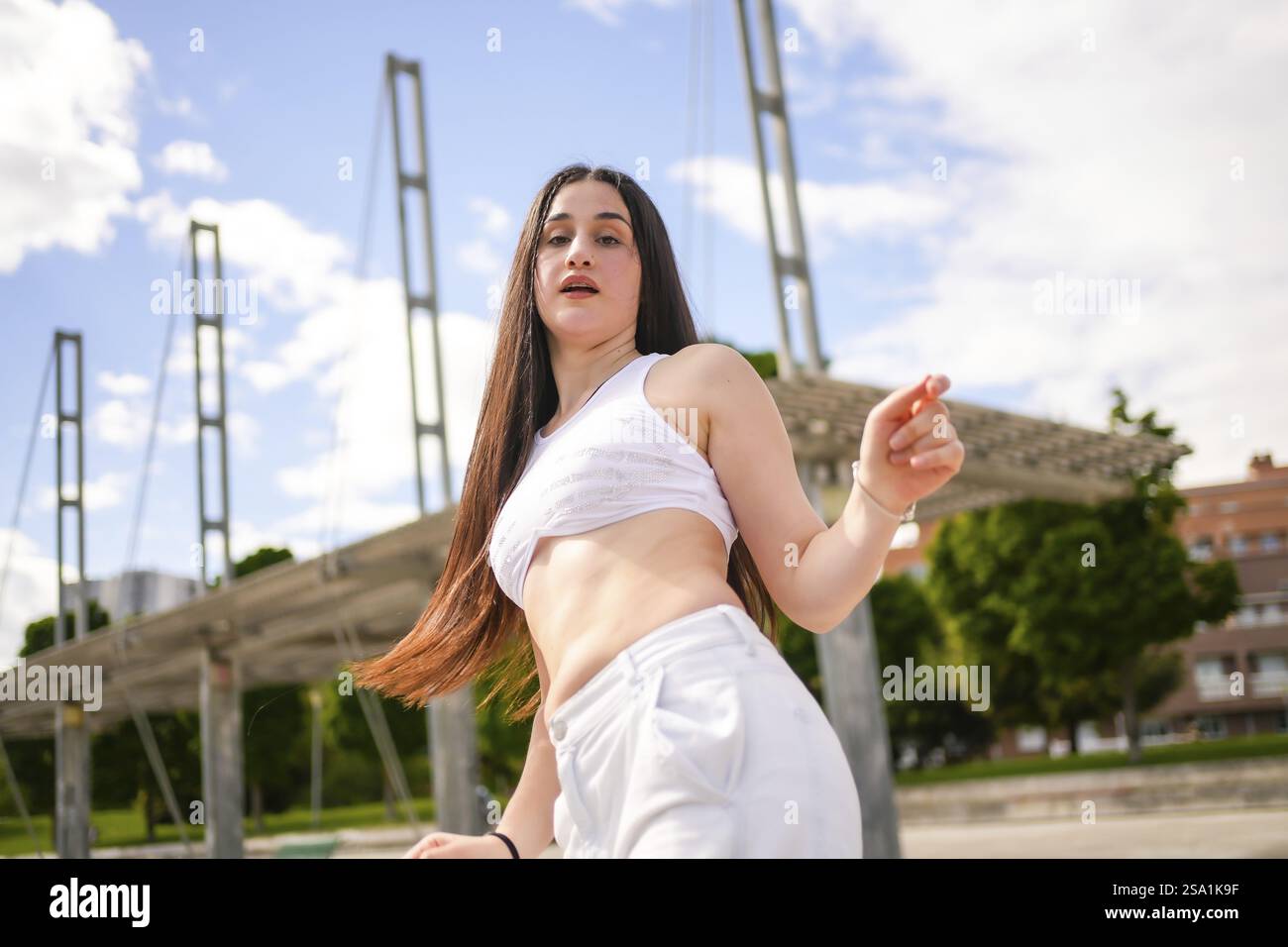 Tiefwinkelfoto einer kaukasischen jungen, selbstbewussten Frau, die in einem Stadtpark im Tanzstil tanzt Stockfoto