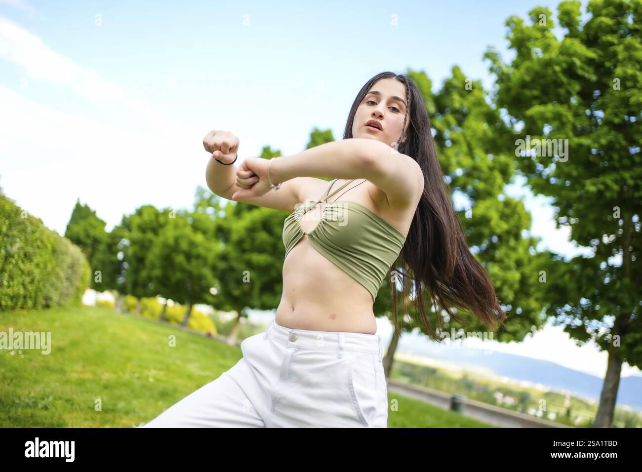 Energiegeladene junge kaukasische Schönheitsfrau tanzt urbane moderne Musik in einem Park Stockfoto