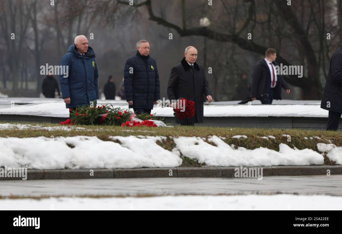 St. Petersburg, Russland. Januar 2025. Der russische Präsident Wladimir Putin rechts, begleitet von dem Präsidentschaftsgesandten Alexander Gutsan links und Sankt Petersburger Gouverneur Alexander Beglov, legte während einer Zeremonie zum 81. Jahrestag der Befreiung Leningrads von der Nazi-Blockade auf dem Piskarjowskoje-Gedenkfriedhof am 27. Januar 2025 in Sankt Petersburg, Russland, einen Rosenstrauß auf ein Massengrab. Putin verlor seinen Bruder Viktor, der während der 872-tägigen Belagerung starb und der tödlichste und zerstörerischste in der Geschichte war. Quelle: Vyacheslav Prokofyev/Kreml Pool/Alamy Live Ne Stockfoto
