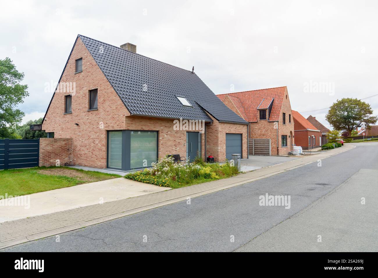 Reihe neuer gemauerter Einfamilienhäuser in einer Wohnsiedlung an einem bewölkten Sommertag Stockfoto