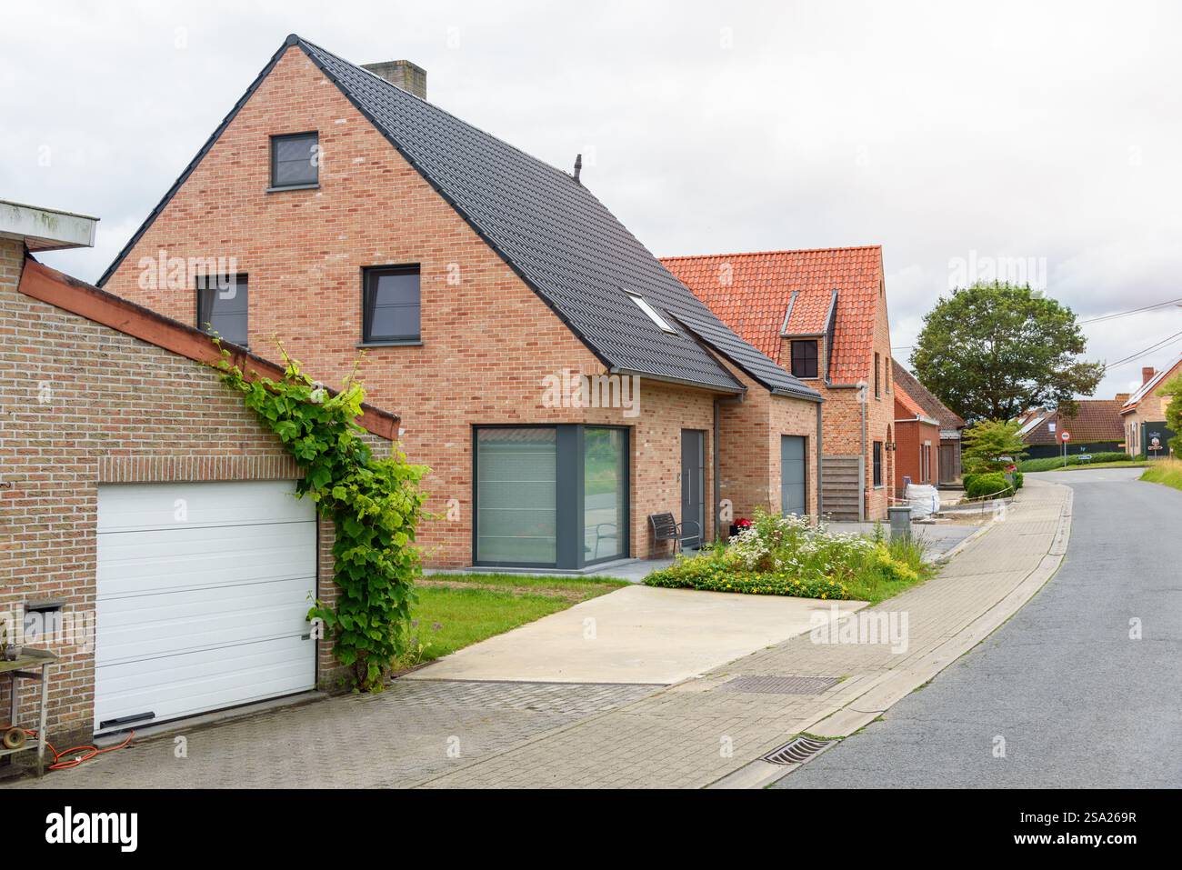 Moderne Backsteinhäuser entlang einer Straße in einer Wohnsiedlung auf dem belgischen Land an einem kühnen Sommertag Stockfoto