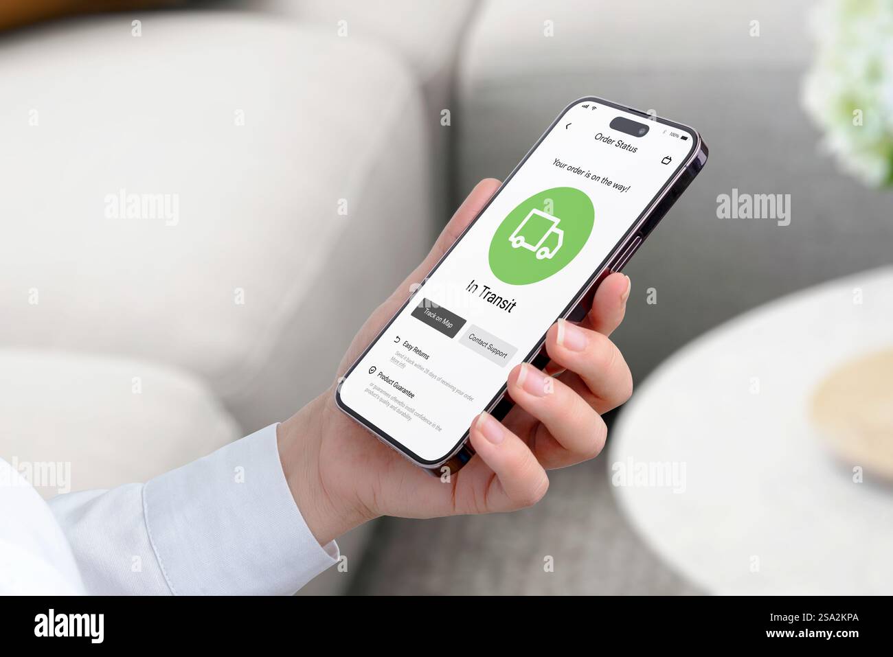 Auf dem Smartphone-Bildschirm wird eine App zur Auftragsverfolgung mit einem LKW-Symbol und dem Status „in Transit“ angezeigt. Die App verfügt über eine Schaltfläche „Track on Map“ Stockfoto