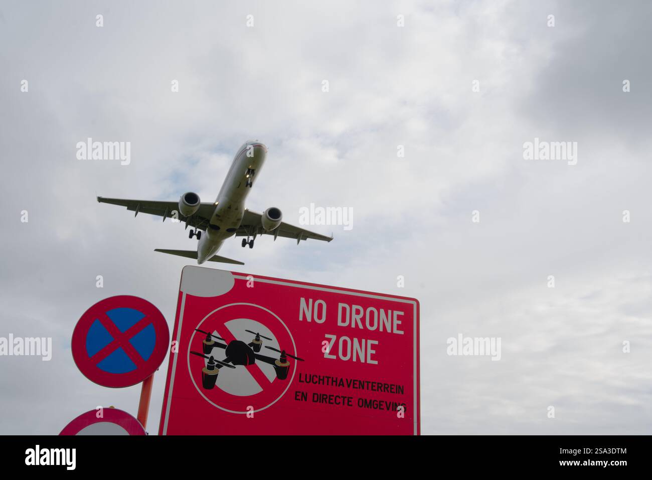 Hochfliegender Widerspruch: Das Flugzeug überquert das Schild „No Drone Zone“ mit niederländischer Warnung Stockfoto