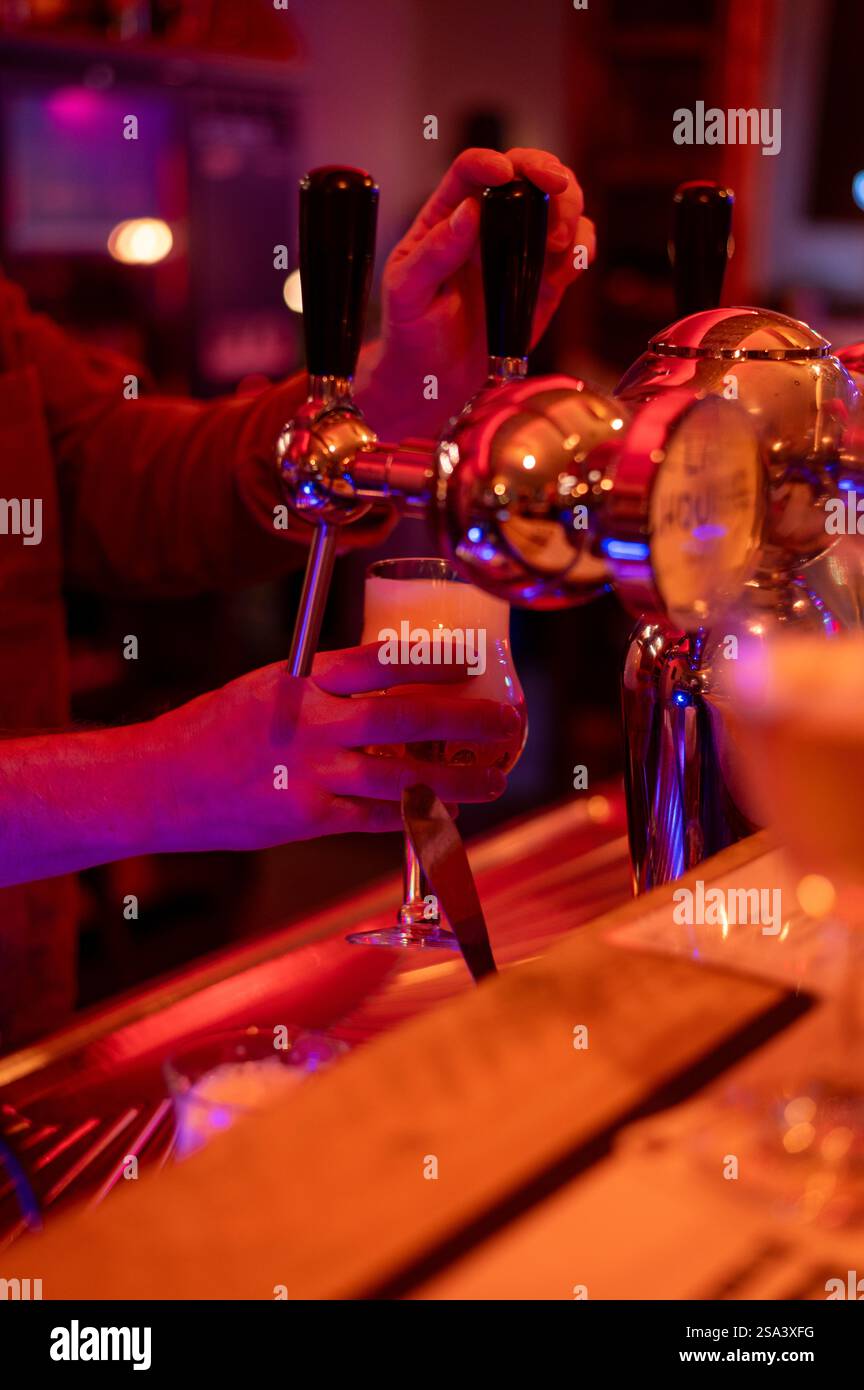 Ein arbeitender Barkeeper hält ein Glas Bier im Nachtclub Stockfoto
