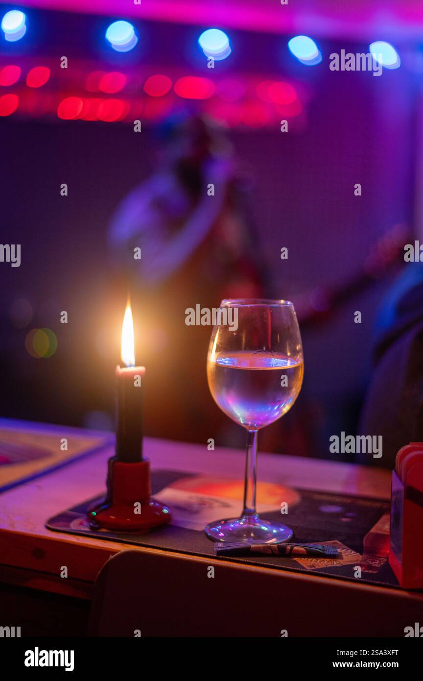 Alkoholgetränk im Glas mit Eis und roter Kerze im Nachtclub Stockfoto