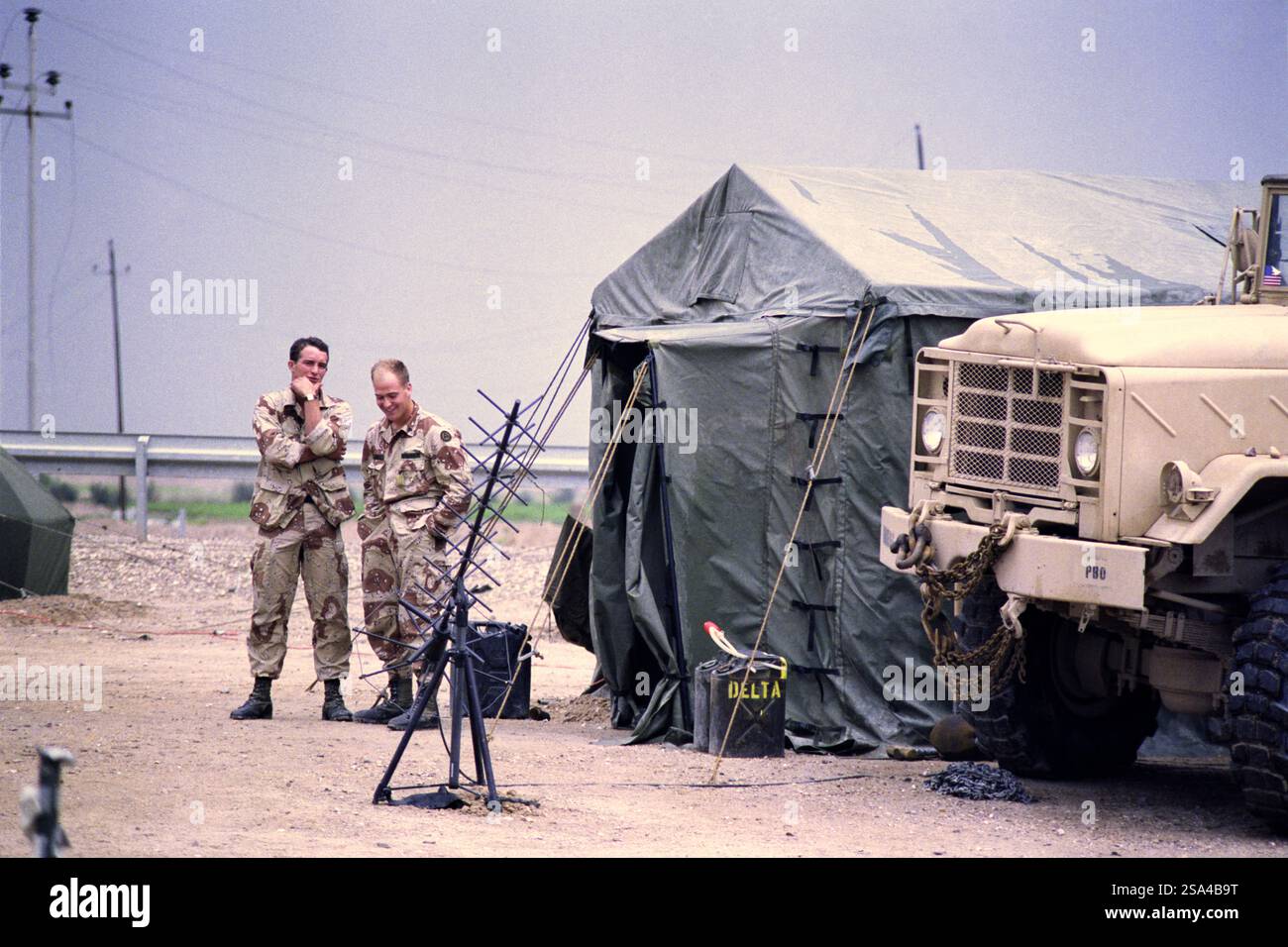 Erster Golfkrieg: 23. März 1991 amerikanische Soldaten stehen neben einer Satcom-Antenne, Teil einer Kommunikationseinrichtung mit einem M939 6x6-Lastwagen neben dem Highway 8, wo er den Highway 1 bei Safwan im südlichen Irak überquert. Es war nur wenige Kilometer vom Flugplatz entfernt, wo der Waffenstillstand unterzeichnet wurde, um die Operation Desert Storm offiziell auszusetzen. Stockfoto