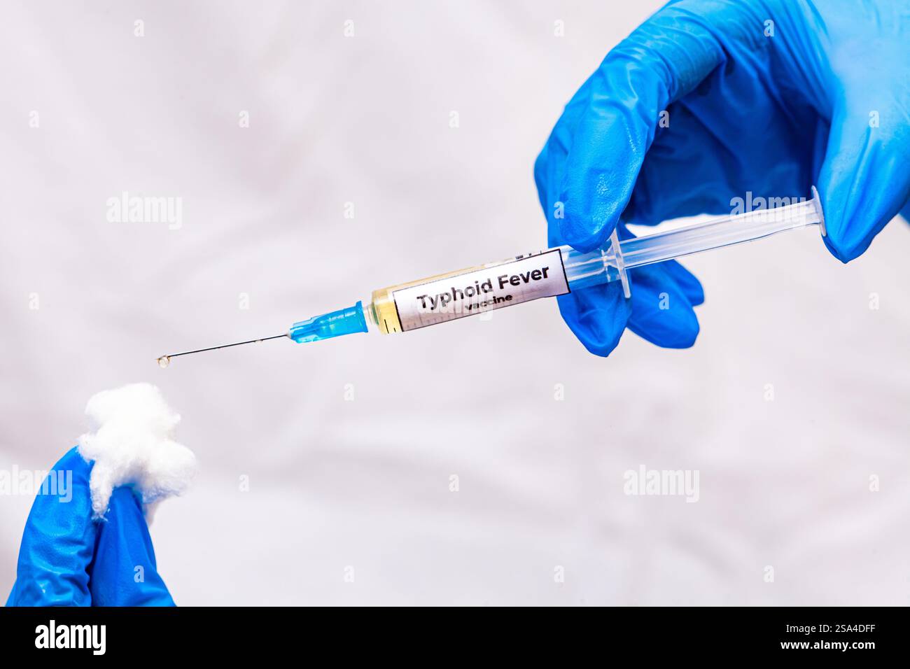 Hände in blauen Handschuhen, die ein Gefäß mit einem gelben Impfstoff halten. Typhus-Impfkonzept. Nahaufnahme, selektiver Fokus Stockfoto