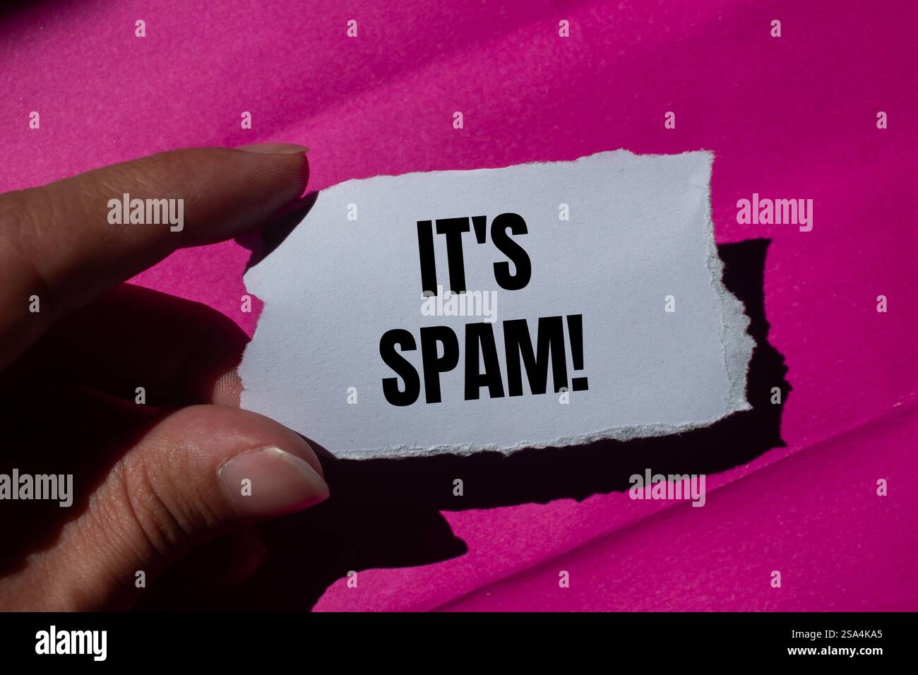Es ist eine Spam-Nachricht auf zerrissenem Papier mit rosa Hintergrund. Konzeptionell ist das Spam-Symbol. Kopierbereich. Stockfoto
