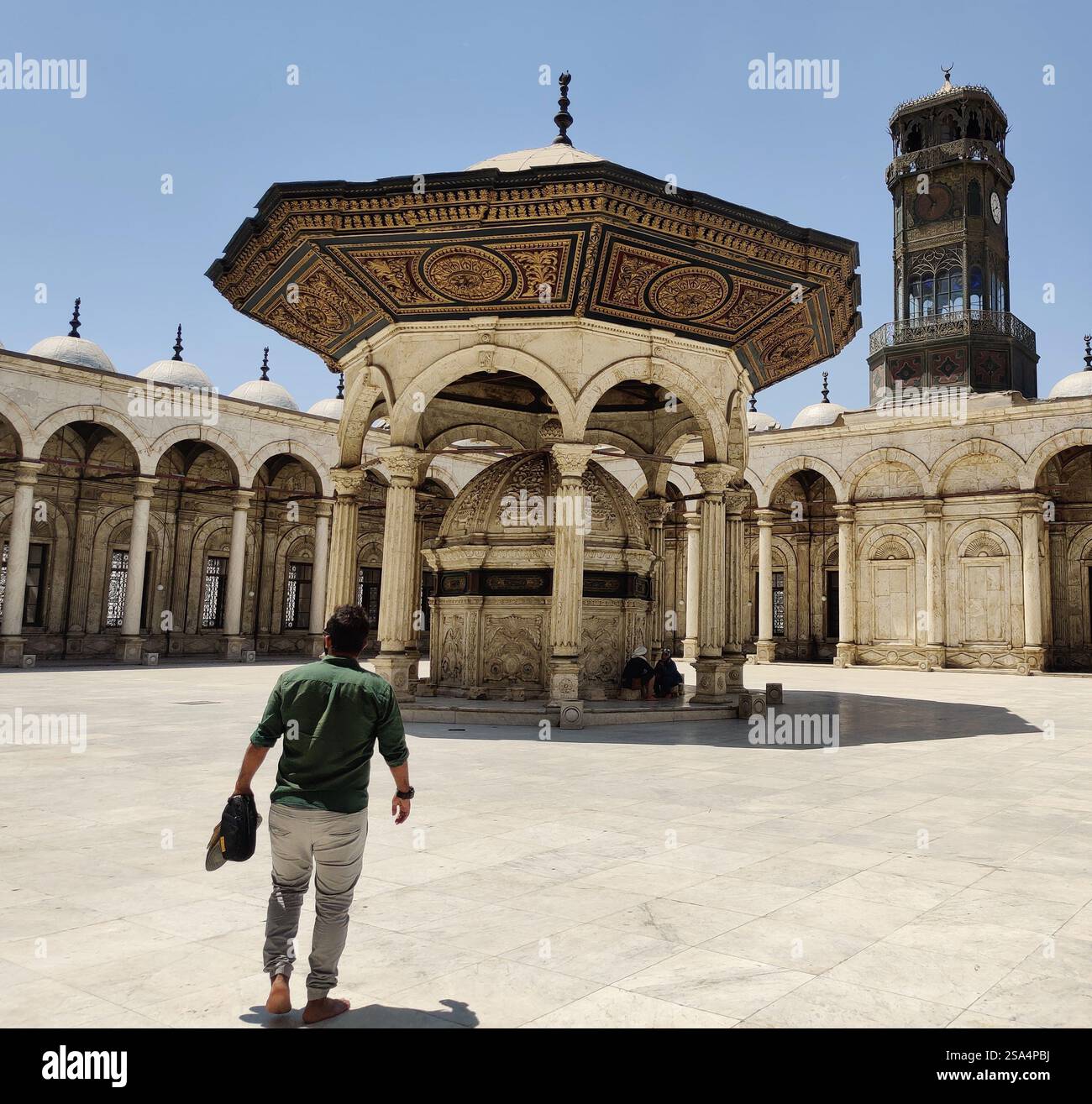 Ein Mann läuft barfuß im Innenhof der Moschee von Muhammad Ali und bewundert den großen Waschbrunnen und die Architektur aus der osmanischen Ära. Stockfoto