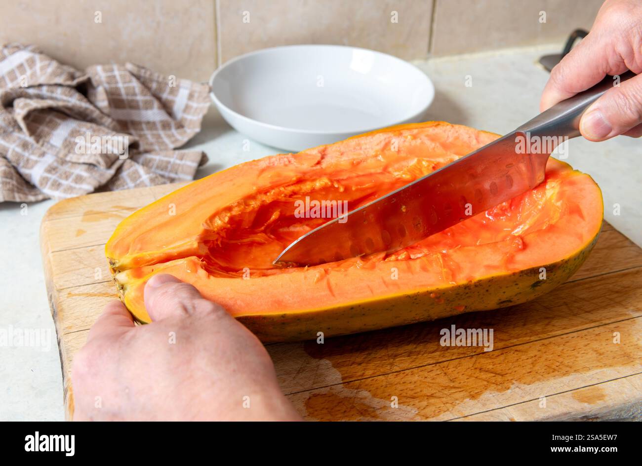 Eine Person, die eine halbe Papaya aufschneidet und die Samen ausgesäubert hat. Stockfoto