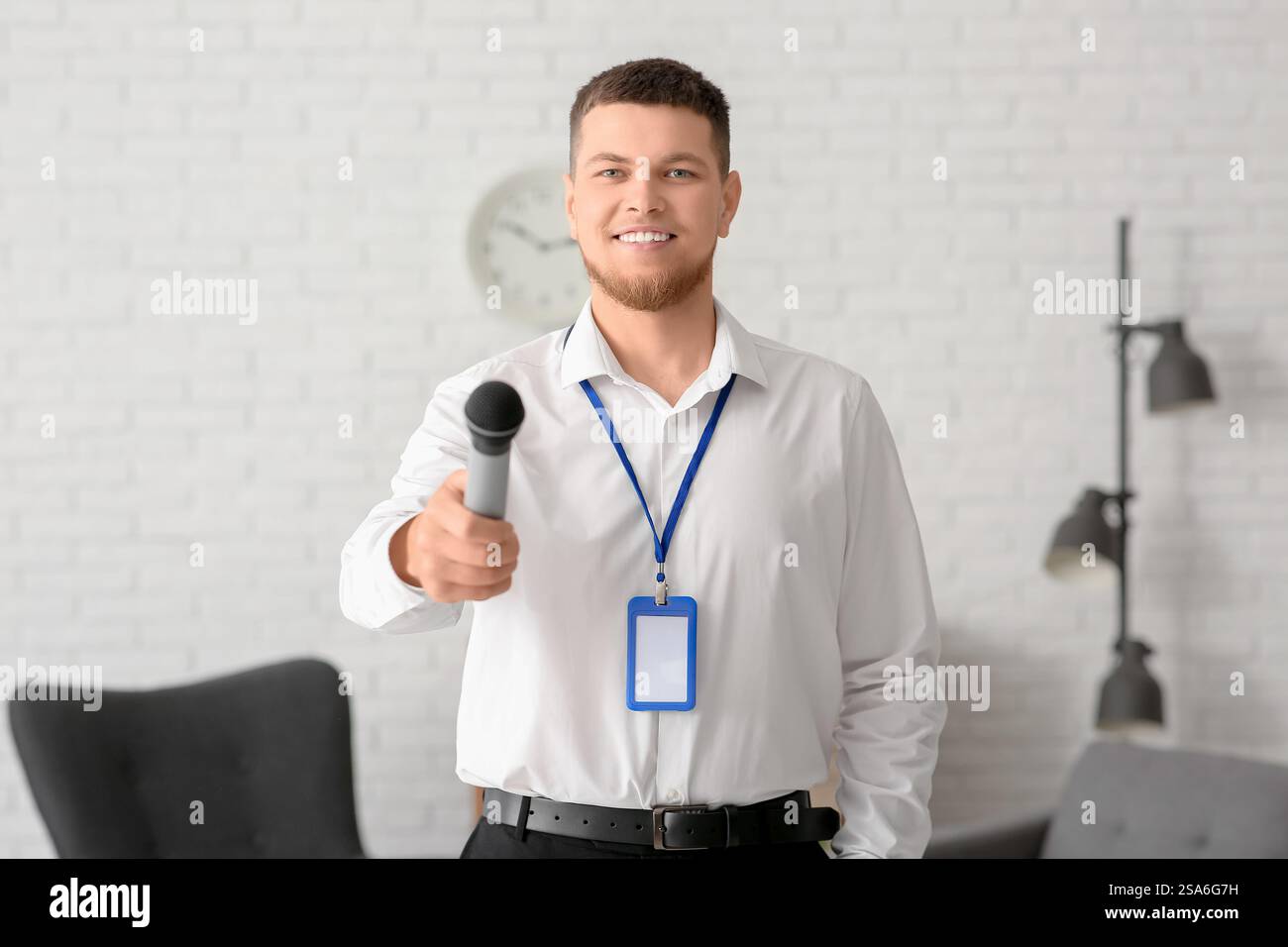 Reporter mit Mikrofon und leerem Namensschild, der im Studio interviewt Stockfoto