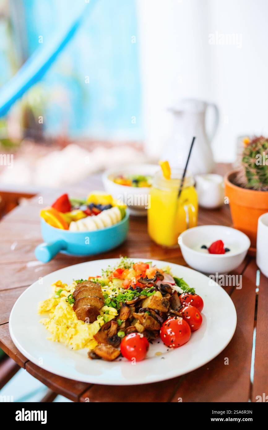 Vegetarisches Frühstück mit Rührei, Bratkartoffeln, Wurst auf Pflanzenbasis, sautierten Pilzen und Kirschtomaten Stockfoto