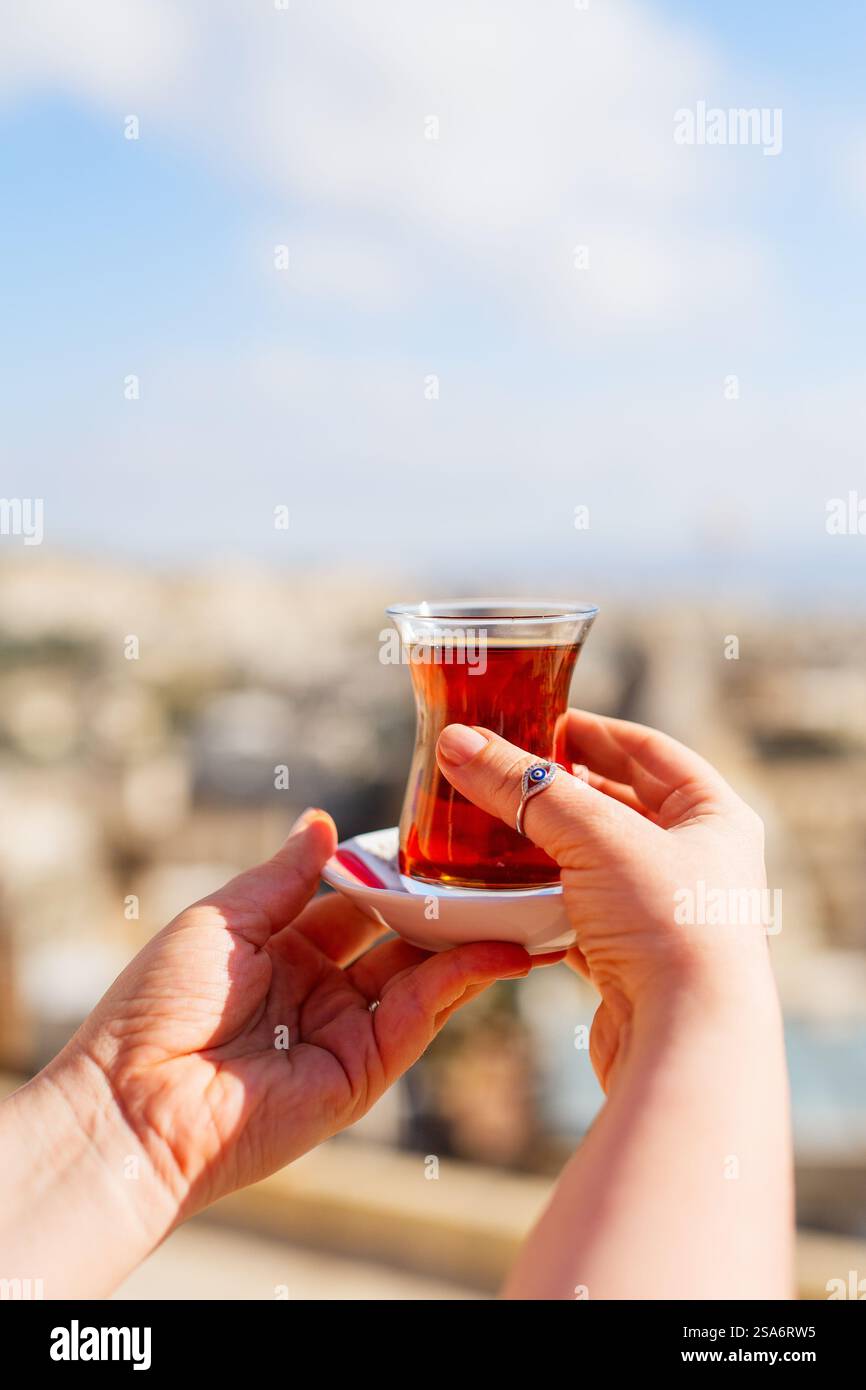 Türkischer Tee in einem traditionellen Glas in der Hand Stockfoto