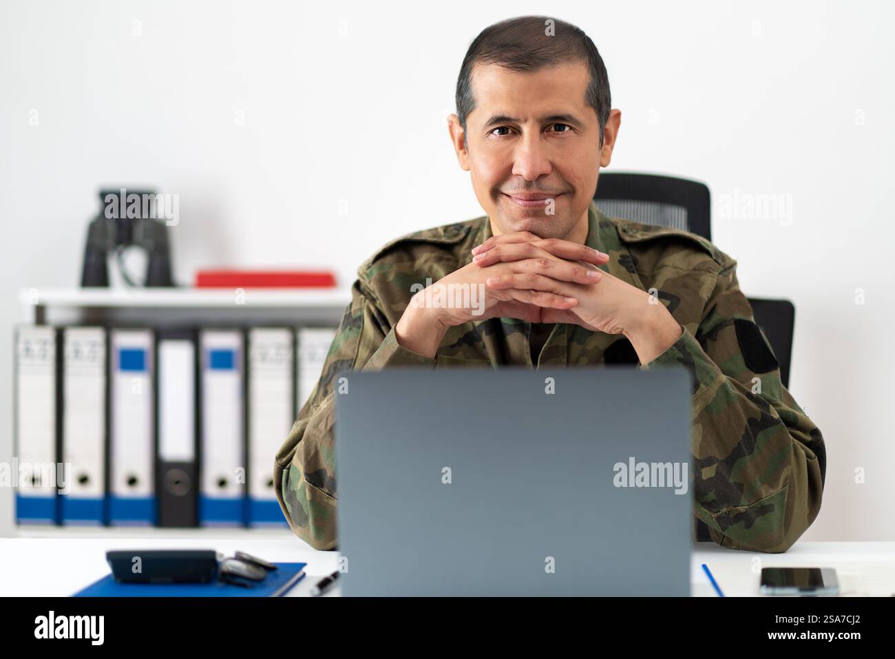Abgeschnittene Aufnahme eines gutaussehenden männlichen Soldaten im Büro und in die Kamera Stockfoto