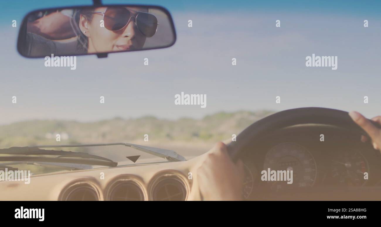 Bild von hellem Schatten über zweirassigem Paar, das am Meer Auto fährt Stockfoto