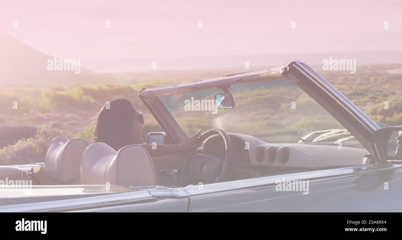 Bild von hellem Schatten über birassischer Frau, die am Meer Auto fährt Stockfoto